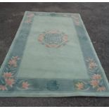 A large modern Chinese washed wool rug with central floral medallion and floral sprays on dark green