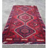 A large handmade rug with central motifs on red ground - some marks - 268cm X 165cm