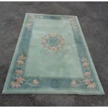 A modern Chinese washed wool rug with central floral medallion and floral sprays on dark green