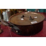An old low copper saucepan with wrought iron handles and sit on lid