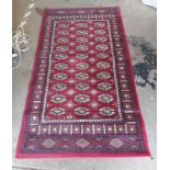 A small machine made Belgian rug with central repeat medallion and geometric border on red ground
