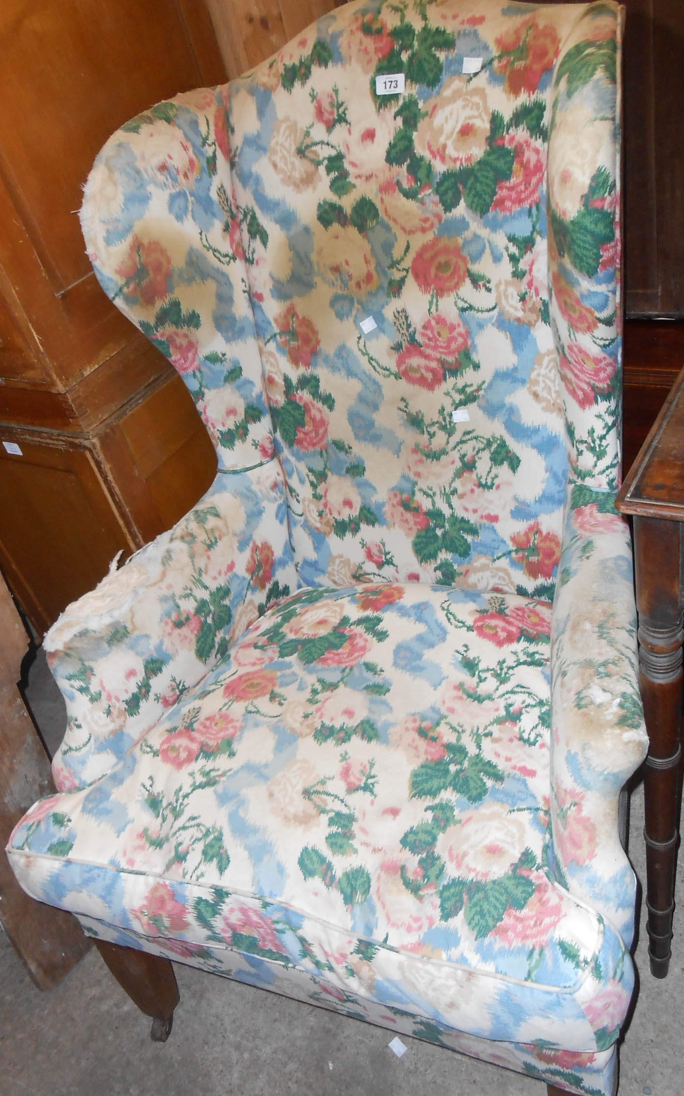 A late 19th Century wingback armchair with remains of upholstery, set on heavy square tapered