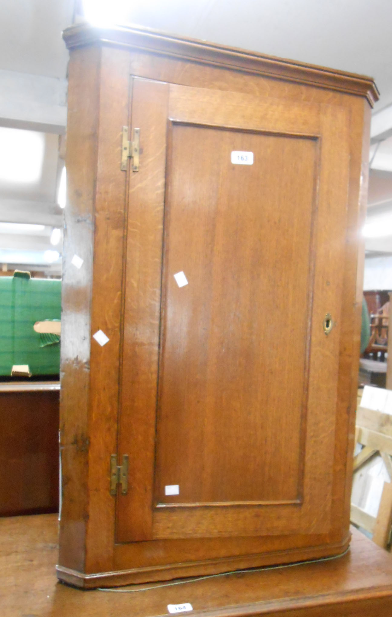 A 62cm oak wall hanging corner cupboard with scalloped shelves enclosed by a panelled door