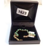 A marked 10k yellow metal bracelet, each link set with a pale green emerald - boxed