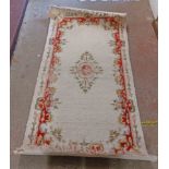 A handmade runner with scrolling foliate border around a central medallion on ivory ground - worn