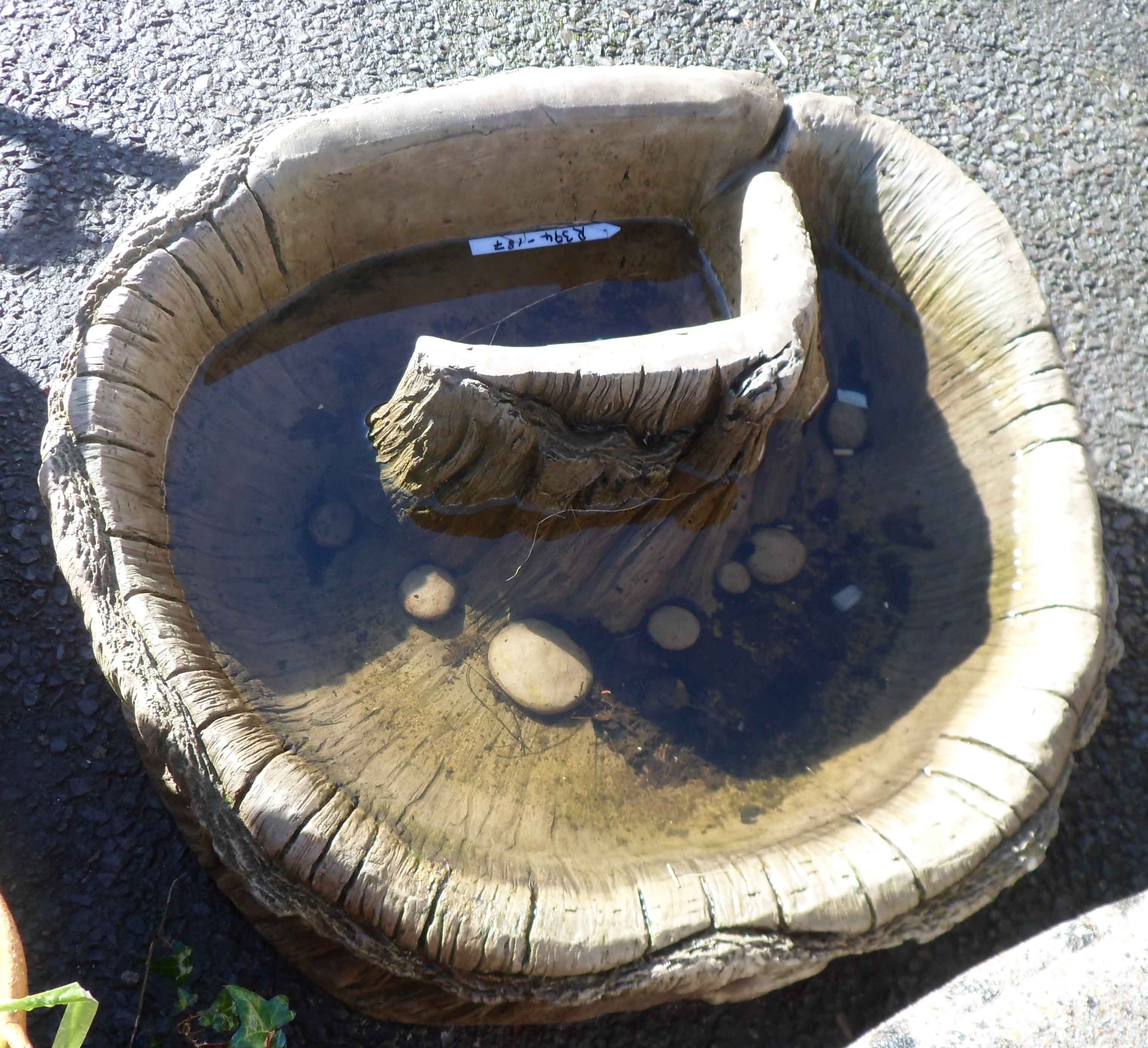 A concrete garden pond of hollowed tree trunk form