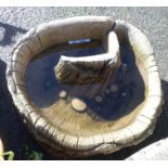 A concrete garden pond of hollowed tree trunk form