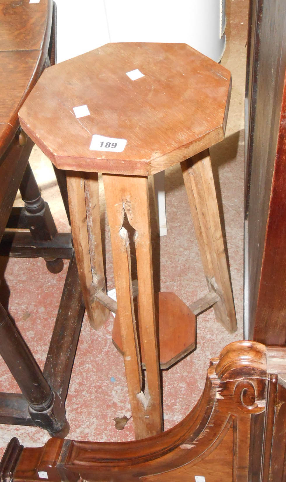 An old two-tier plant stand with octagonal surfaces and pierced decoration to legs