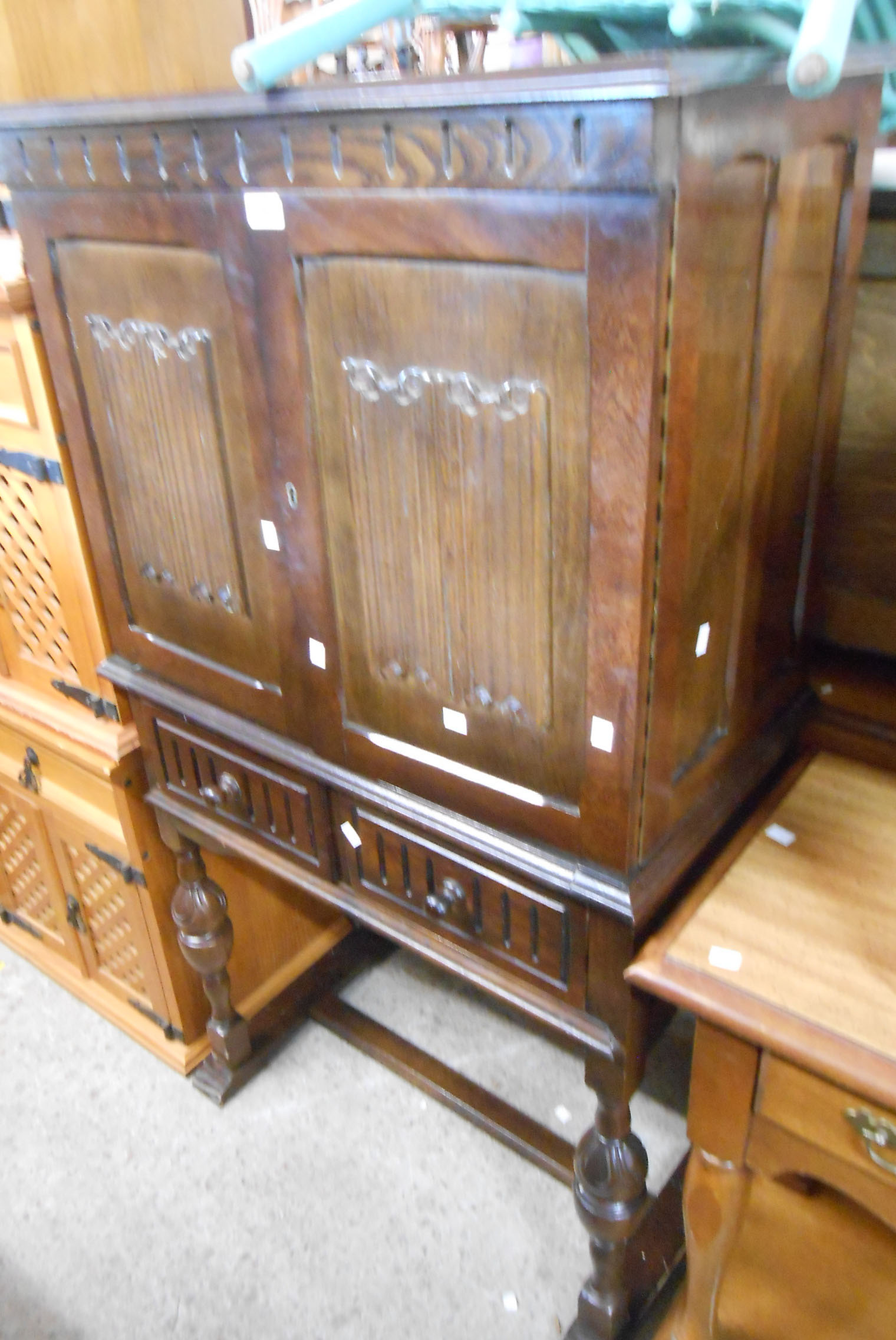 A 76cm vintage stained mixed wood cabinet enclosed by a pair of linen fold panelled doors with two