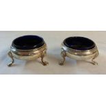 A pair of late Georgian silver salts with blue glass liners, set on triple hoof pattern feet - marks