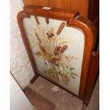 A 1930's stained and polished mixed wood fire screen with embroidered still life under glass