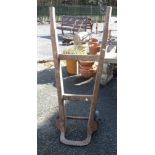 An old sack truck with wooden frame, wrought iron bracket and rubber wheels