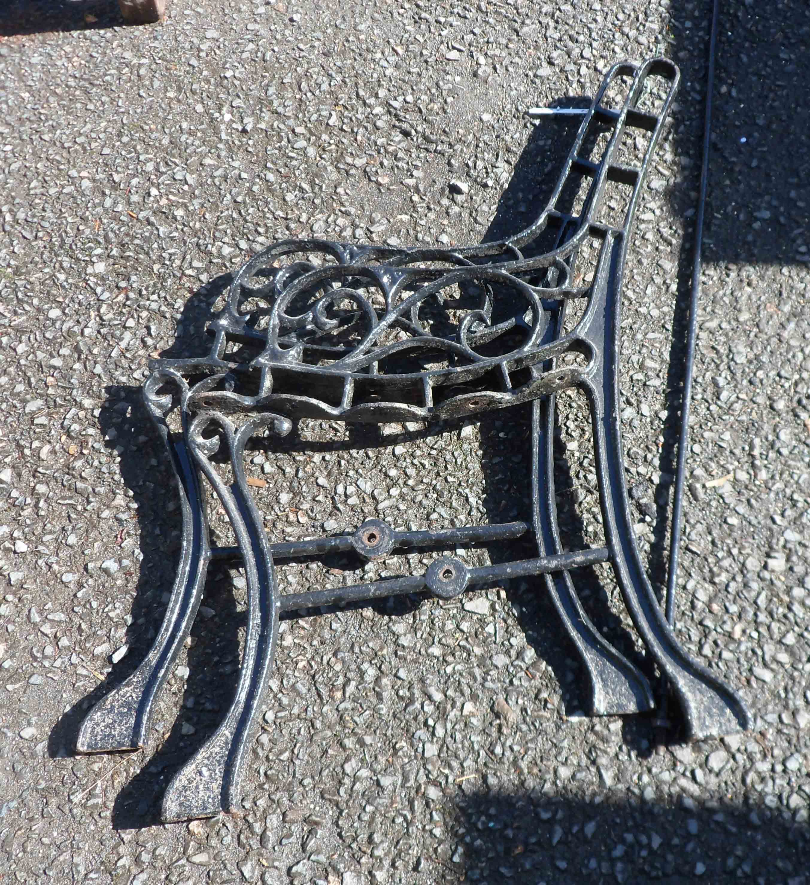 A pair of painted cast iron bench ends and connecting rod