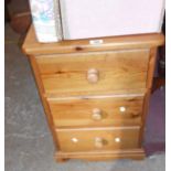 A modern pine bedside chest of three drawers