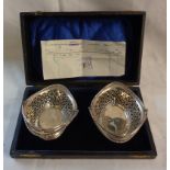 A cased pair of silver bon bon dishes with swing handles and repeat pierced decoration -