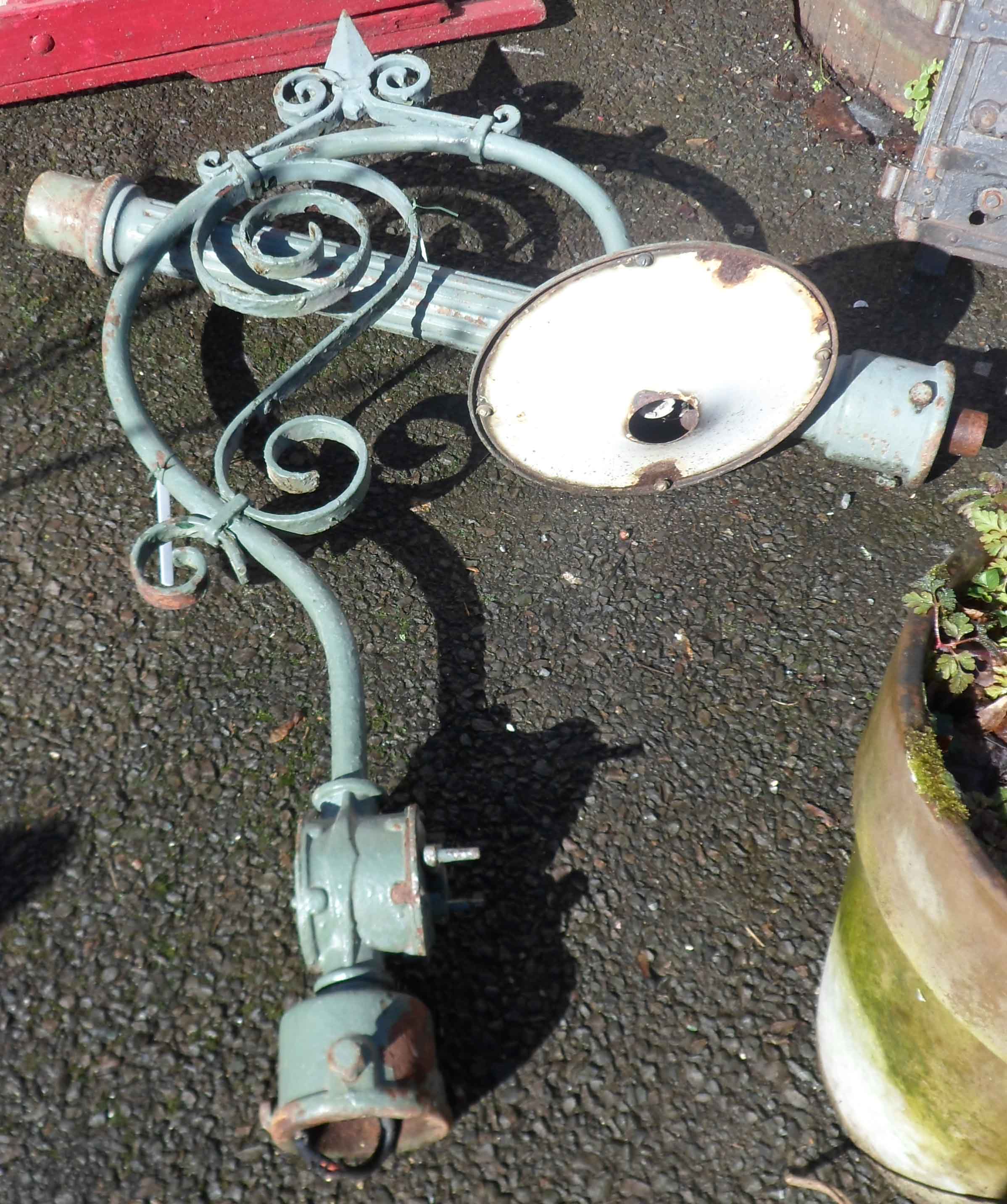 An old outside electric lamp with cast iron pillar and wrought iron bracket with scrolling