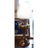 An old brass oil lamp with glass chimney and moulded amber glass shade with floral panel decoration