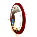 A late Victorian bubble glass oval wall mirror in upholstered frame, set with brass sconce and