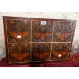 A wooden panel set with six Victorian dust pressed tiles, each decorated in relief with an owl and