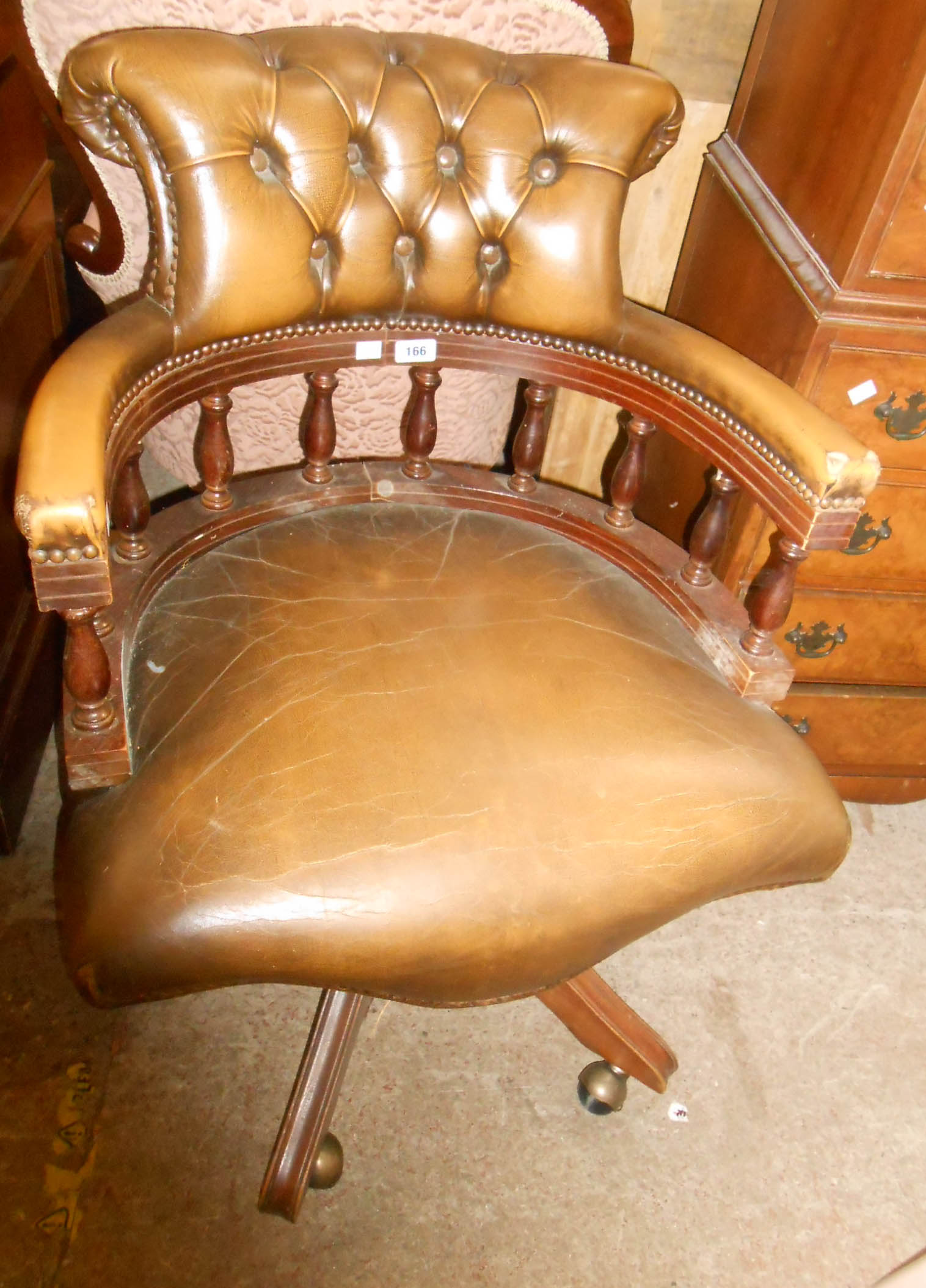 A reproduction captain's chair with studded button back upholstery, set on quintuple splayed legs