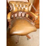 A reproduction captain's chair with studded button back upholstery, set on quintuple splayed legs