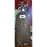 An old glass mesh covered soda siphon with chrome plated fittings