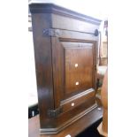 A 60cm antique oak wall hanging corner cupboard with scalloped shelves enclosed by a panelled door