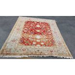 An early 20th Century handmade wool carpet with stylised repeat motifs on red ground within triple