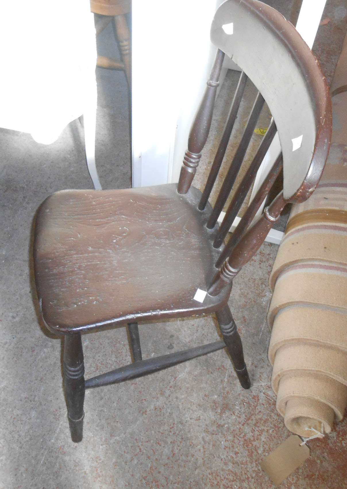 An antique stained wood stick back kitchen chair with moulded solid elm seat, set on ring turned