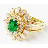 An 18ct. gold ring, set with central oval emerald within stepped concentric bands of brilliant and