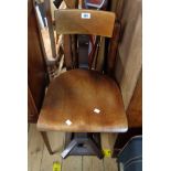 A vintage Singer sewing chair with curved back rail and bentwood seat panel, set on a heavy cast