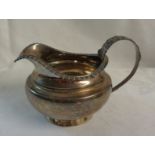 A silver cream jug with cast decoration to handle and rim - London 1826