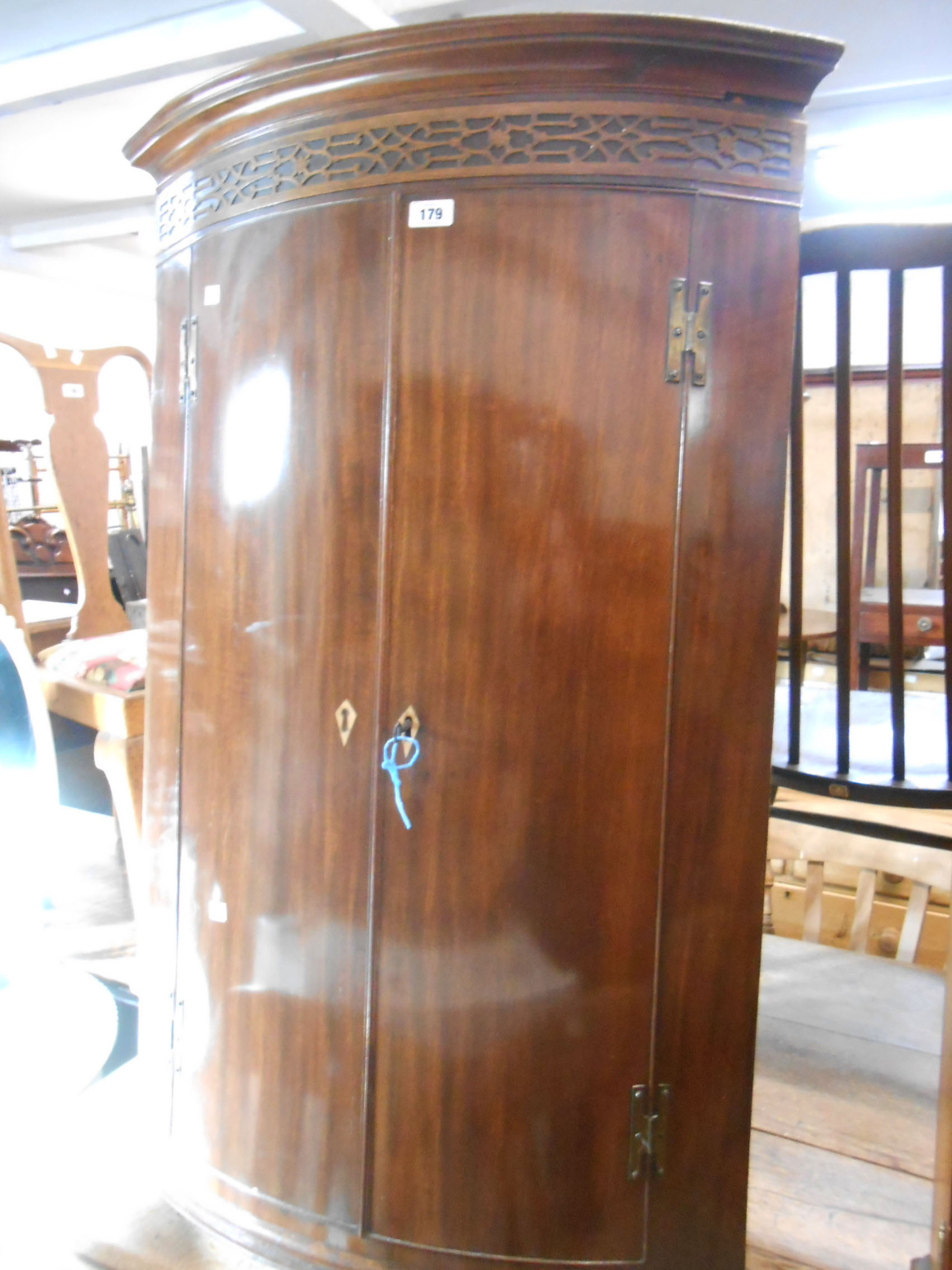 A 72 cm antique mahogany wall hanging bow front corner cabinet with blind fretwork decoration to top