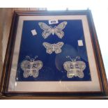 A framed and glazed panel containing four hand worked lace butterflies