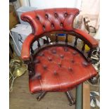 A reproduction stained wood framed captain's chair with red button back leather upholstery, set on