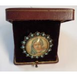 A white metal mounted and blue bead bordered portrait miniature of a woman wearing a headdress -