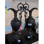 A pair of spelter garniture ewers with applied patination on turned wooden plinths