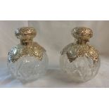 A pair of ornate silver flip-top and pierced shoulder mounted cut glass spherical scent bottles a/f