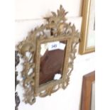 A small gilt metal framed oblong wall mirror with folding easel back and scroll decoration