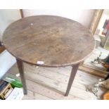 A 83cm diameter antique oak kitchen table with four plank top, set on square tapered and chamfered