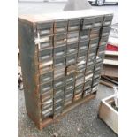 A vintage green painted metal workshop pigeonhole drawer unit holding a large quantity of
