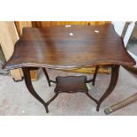 A 66cm Edwardian stained walnut two tier occasional table with shaped surfaces