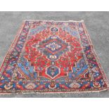 A vintage Turkish handmade rug, with polychrome floral motifs within a wide decorative border on red