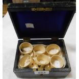 A leather covered jewellery case containing a set of six Japanese carved bone napkin rings each