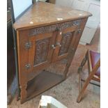 A 65cm 20th Century carved oak freestanding corner cabinet, set on shaped front supports with