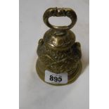 A cast brass table hand bell decorated with stork and lilypad motifs and a grotesque fish handle -