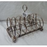 A silver toast rack with shaped dividers, set on ball feet