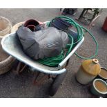 An old metal framed plastic wheelbarrow containing a selection of garden pots