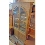 A 1.1m early 20th Century oak corner cabinet with pair of glazed panel arched doors top over a