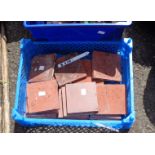 A small plastic crate containing a quantity of terracotta floor tiles